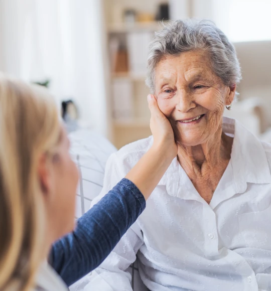 Eine lächelnde Seniorin die von einer Angehörigen gepflegt wird